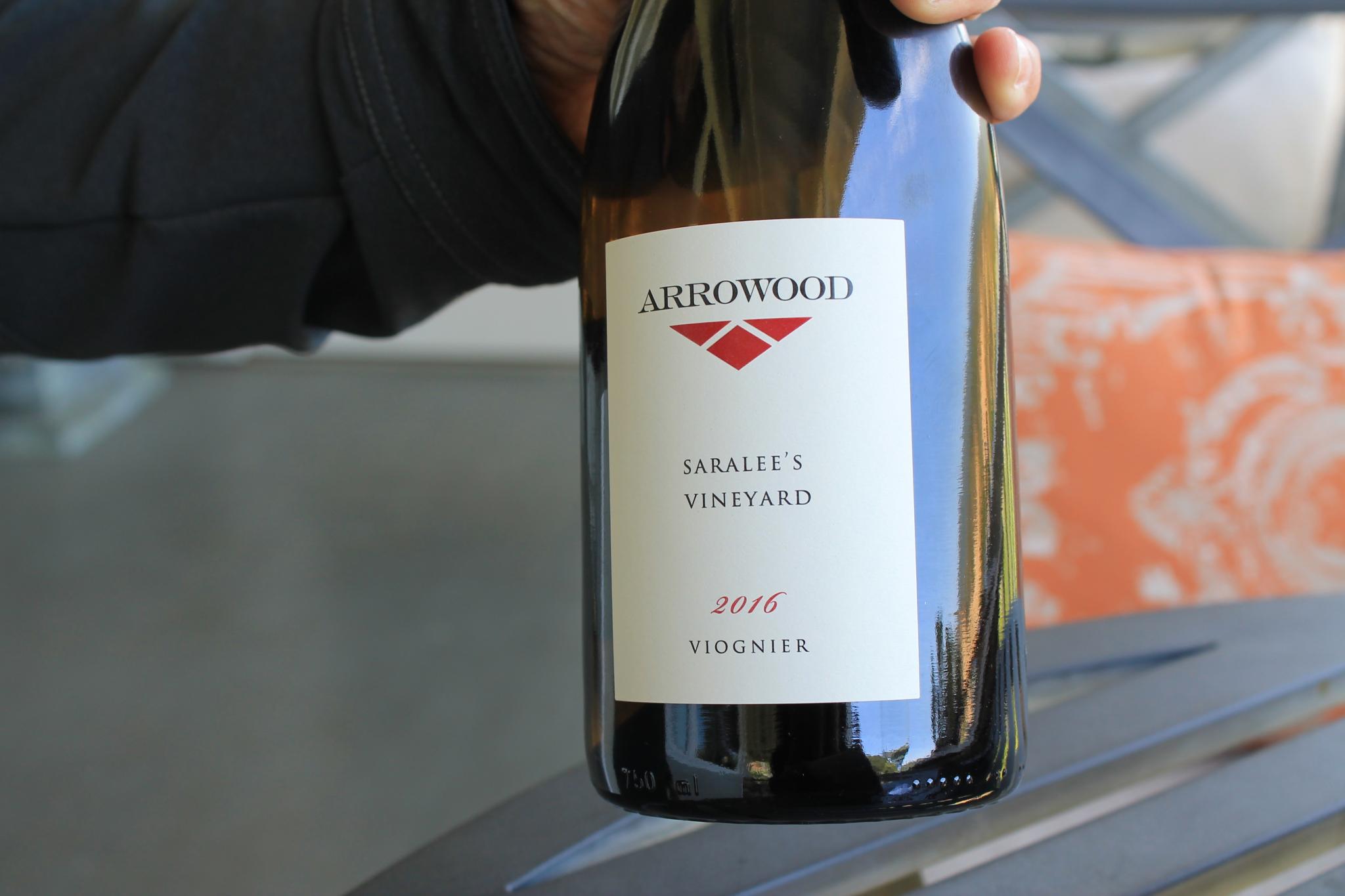 A hand holding a bottle of Arrowood 2016 Saralee's Vineyards viognier.
